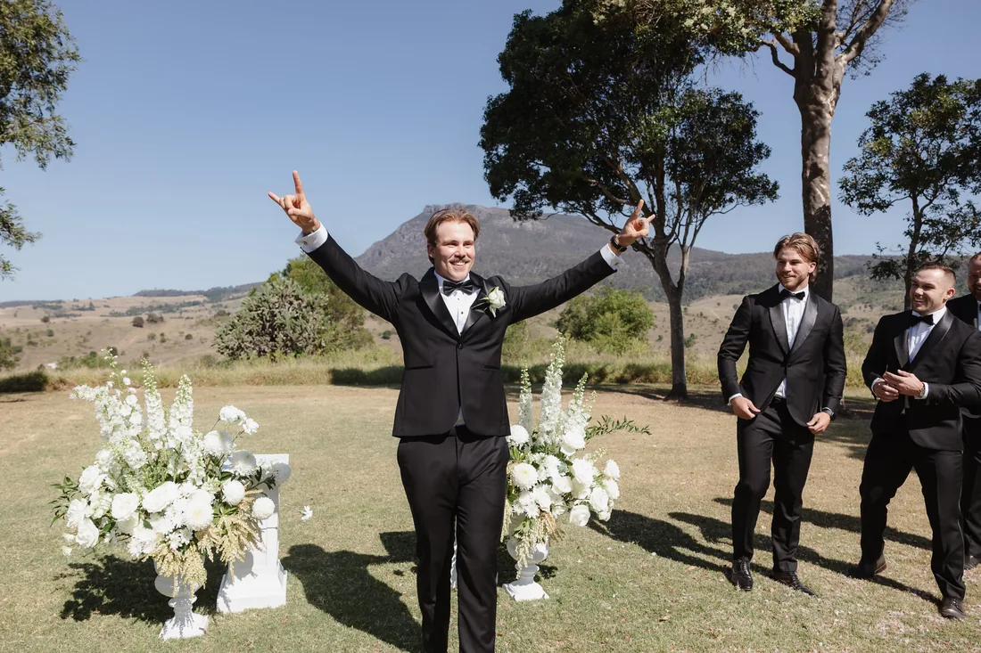 Groom celebrating with groomsmen before the ceremony, floral urns either side