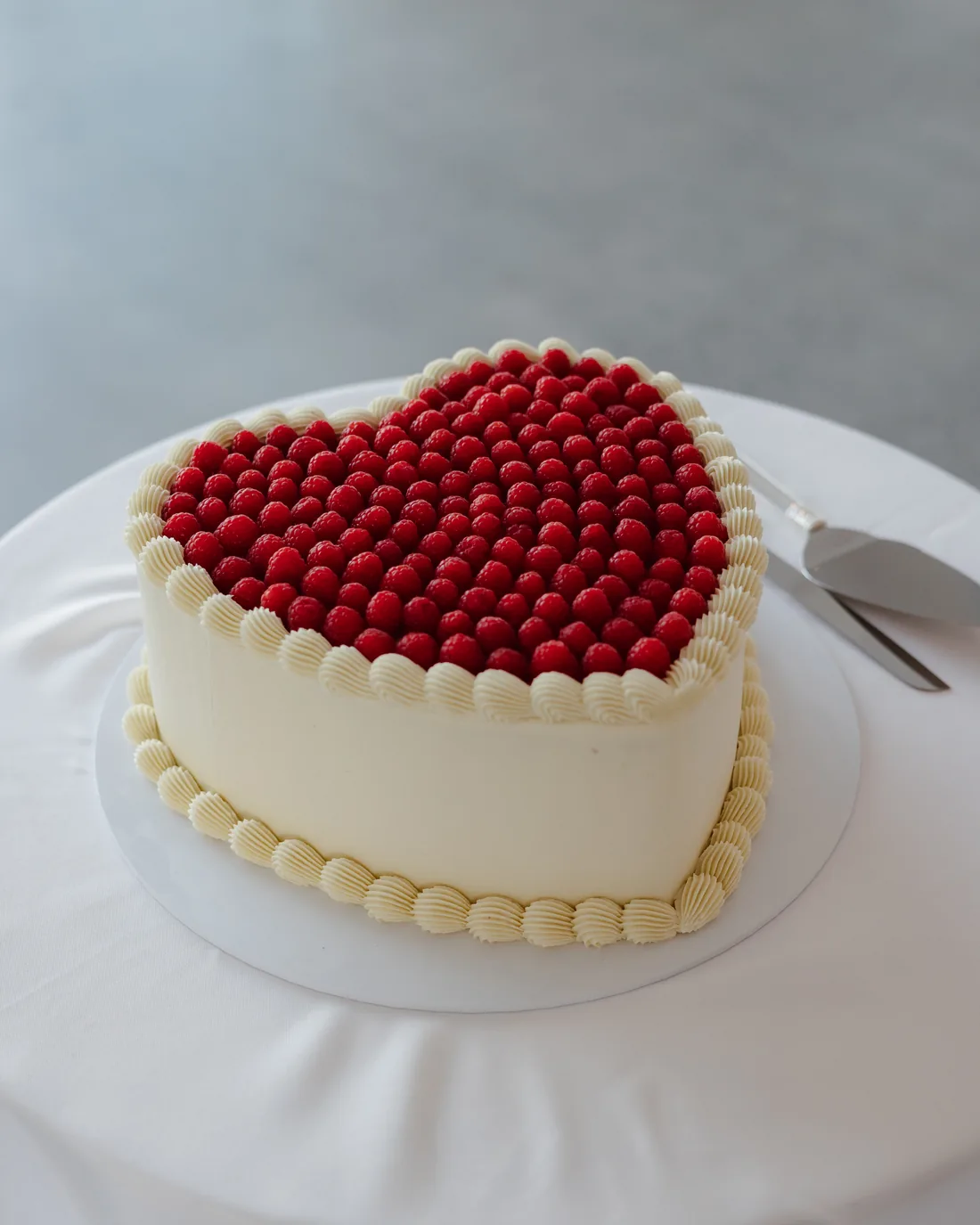 Heart-shaped wedding cake topped with fresh raspberries
