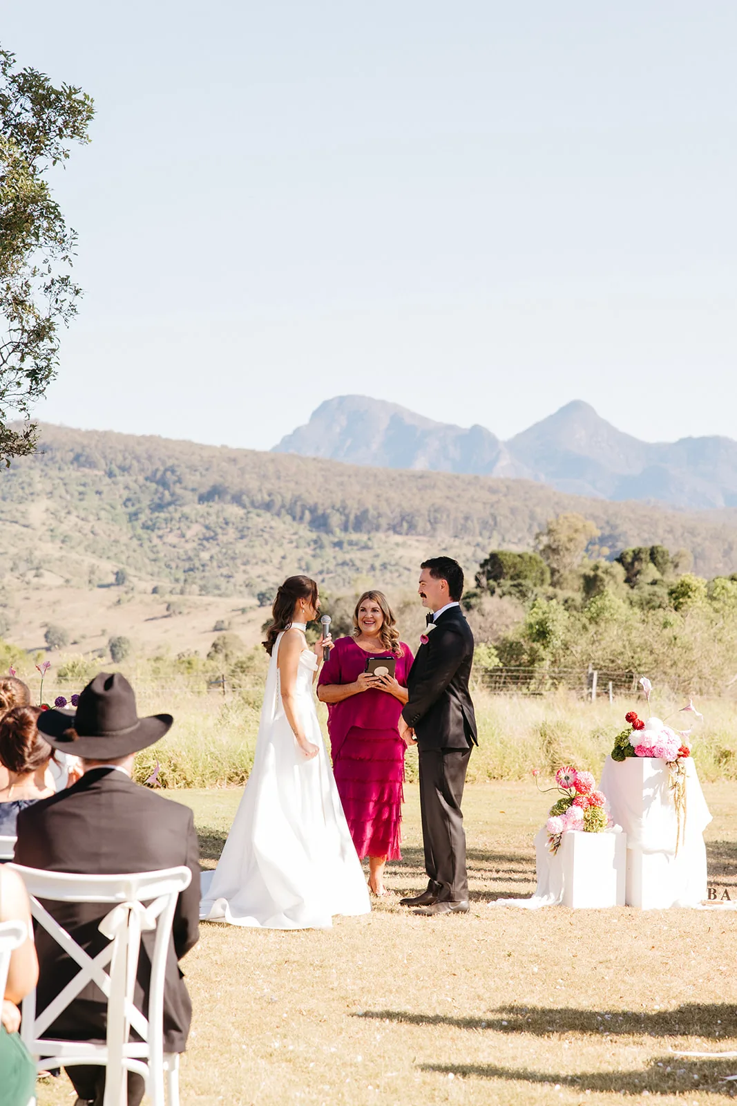 Ally and Braydon exchanging vows with the celebrant, mountain views behind