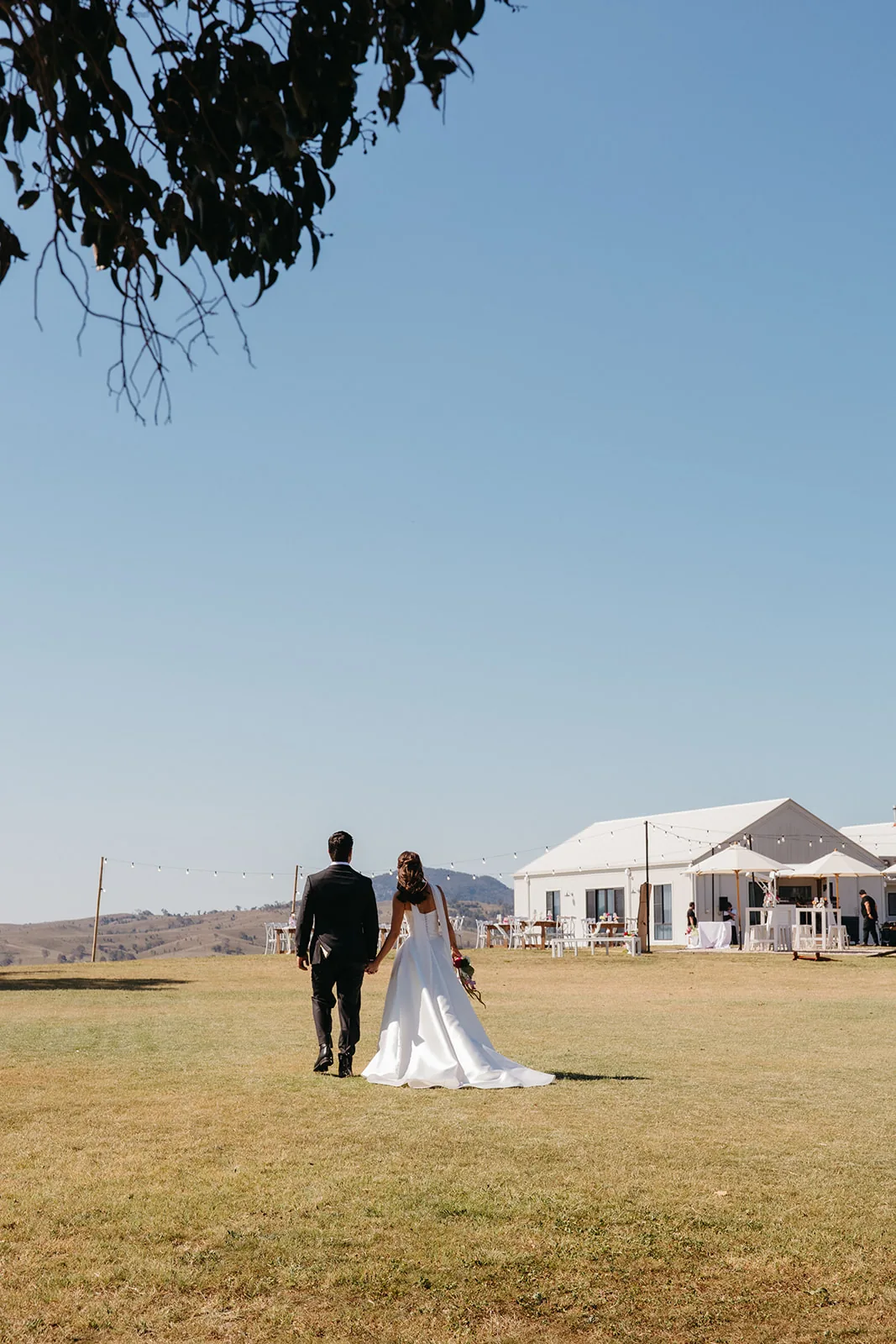 Ally and Braydon walking hand in hand towards the reception building