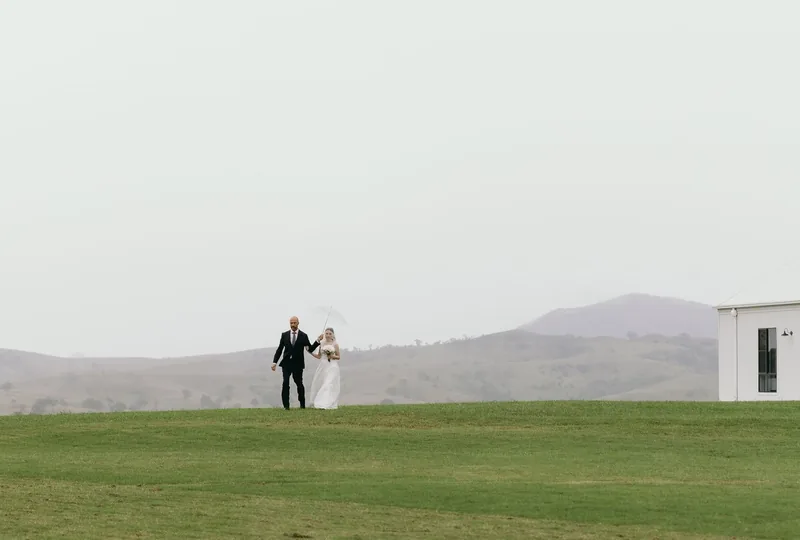 Daniel and Emily walking together across the misty lawn towards the reception building
