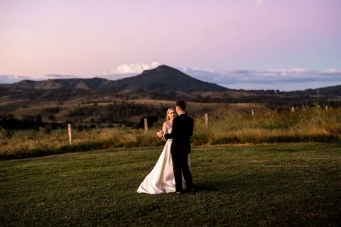 A couple on the lawn under a pink dusk sky