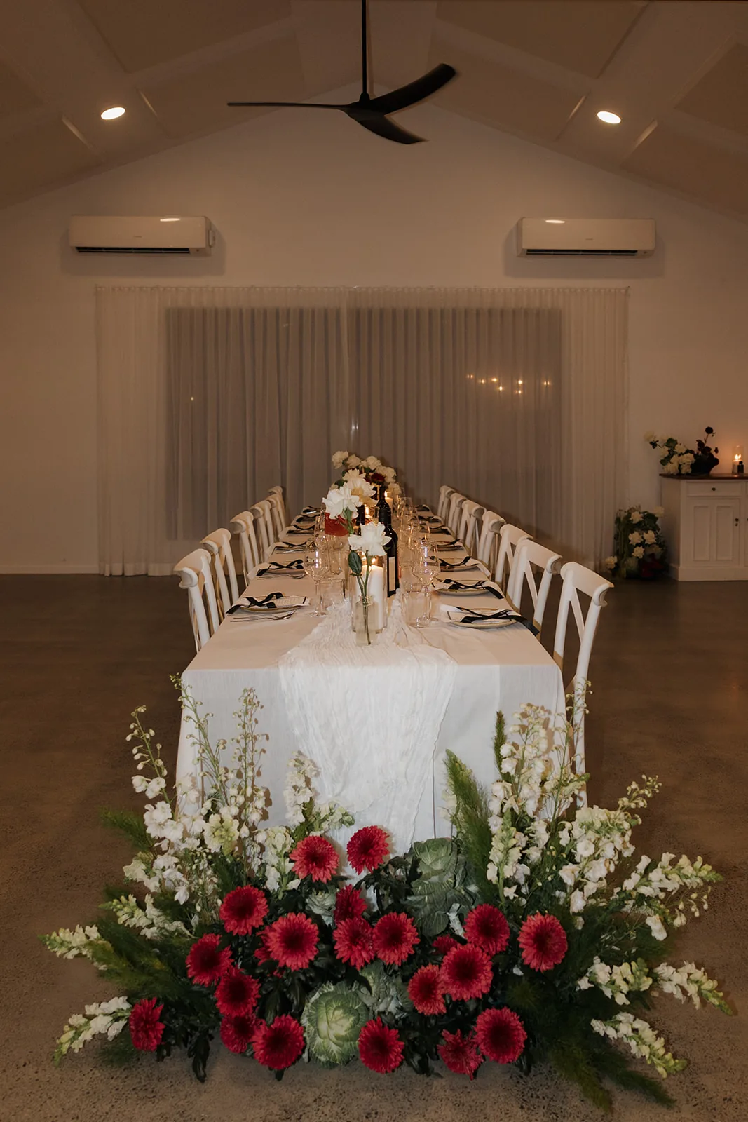 Long reception table set with candlelight, wine and a sheer table runner
