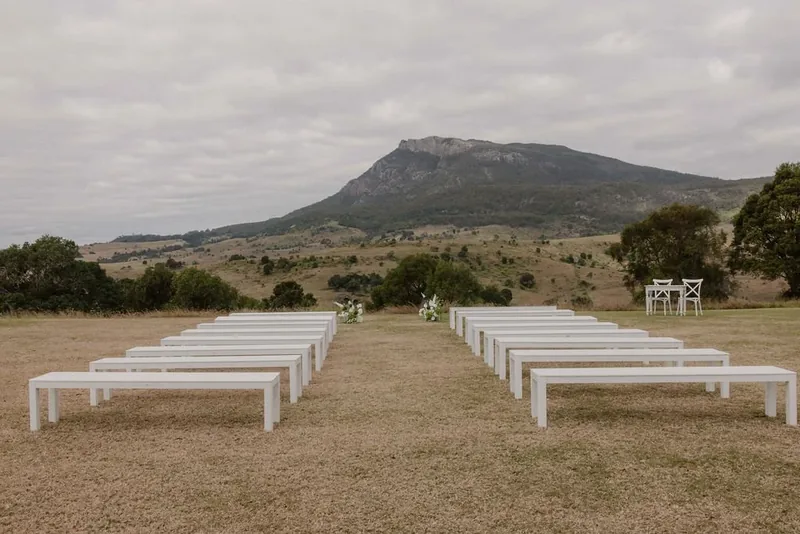 White bench seats set in rows for a ceremony, Mount Maroon behind