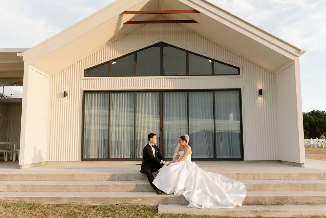 Laura and Connor sitting together on the venue steps at golden hour