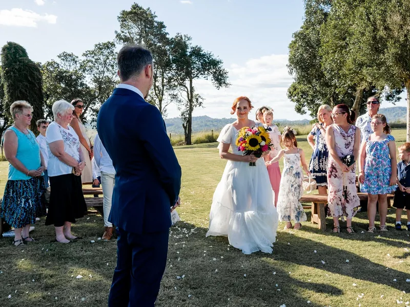 A small ceremony on the lawn under the trees, guests standing close around the couple
