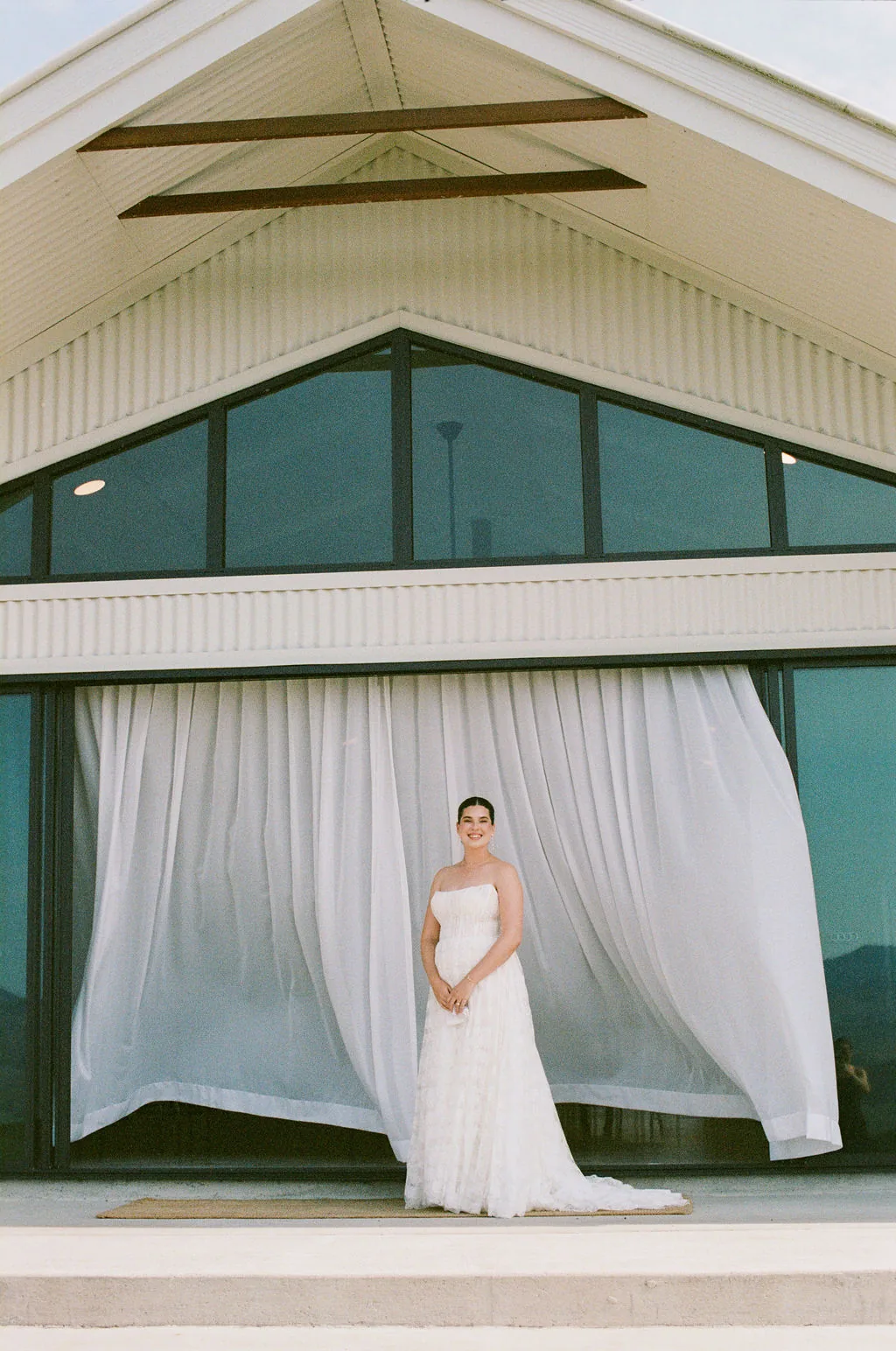 Bride standing in front of sheer curtains on the reception building's veranda