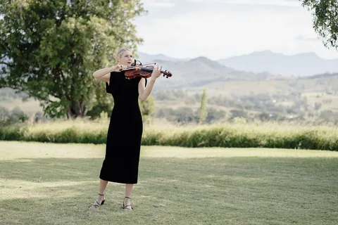 A violinist playing on the lawn, the ranges behind