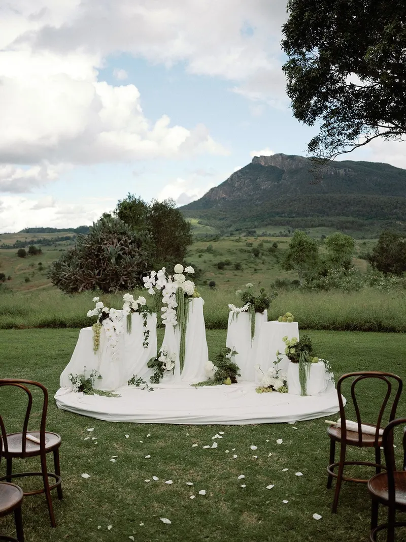 A styled ceremony set among the trees with Mount Maroon behind it
