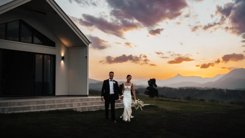 Gorgia and Nick walking beside the reception building as the sun sets behind the mountains
