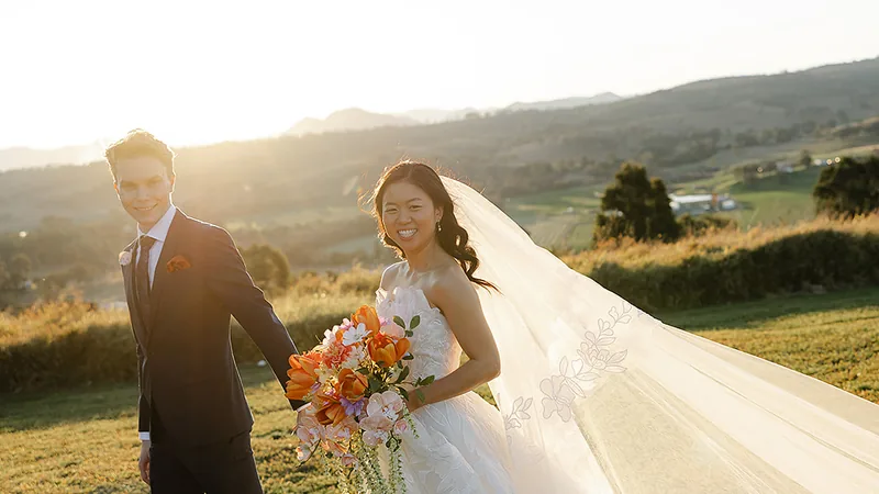 Jamie and Tyler at golden hour, veil catching the light over the hills
