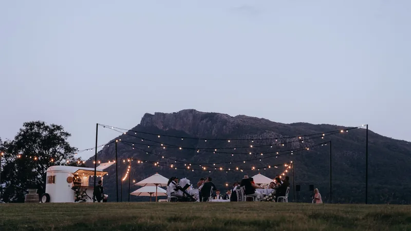 The reception at dusk, festoon lights strung beneath Mount Maroon