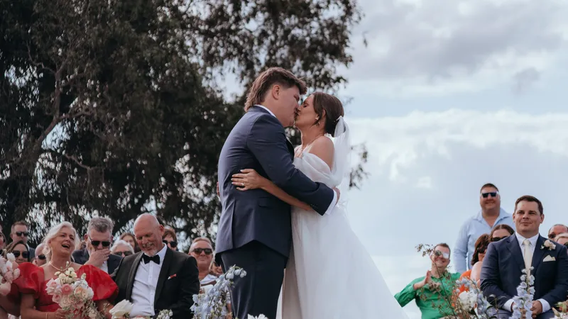 Jorjia and James kissing at the end of the aisle as their guests cheer