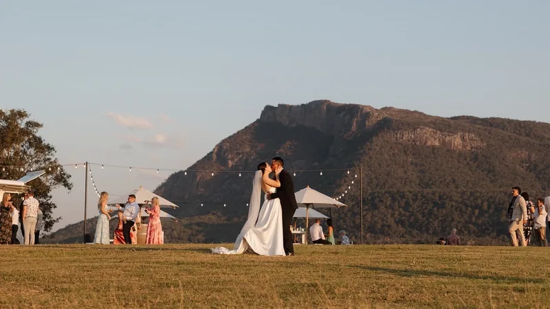 Megan and Lyall during their reception, Mount Maroon behind the festoon-lit lawn
