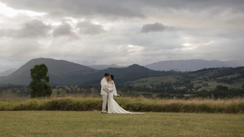 Nick and Mabel kissing on the lawn under a moody sky, the ranges behind them